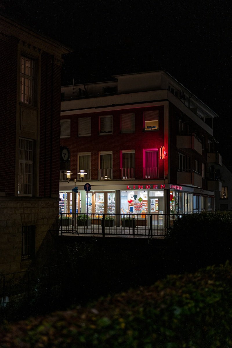 Home Building illuminated at night with red neon sign.